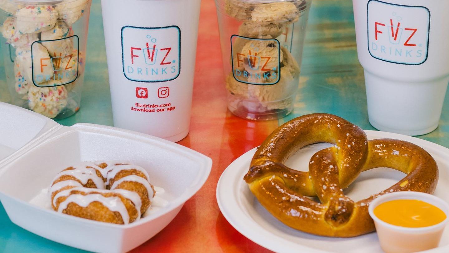 FiiZ cups with dough bites, a soft pretzel with cheese sauce and iced cinnamon bites on a colorful table
